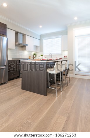 Interior design of a luxury modern kitchen with nicely decorated and served island table with bar style chairs. Vertical.