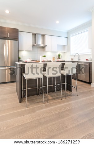 Interior design of a luxury modern kitchen with nicely decorated and served island table with bar style chairs. Vertical.