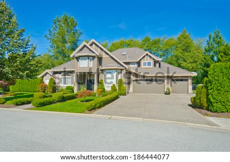 Big custom made luxury house with nicely landscaped front yard, triple doors garage and long and wide driveway in the suburbs of Vancouver, Canada.