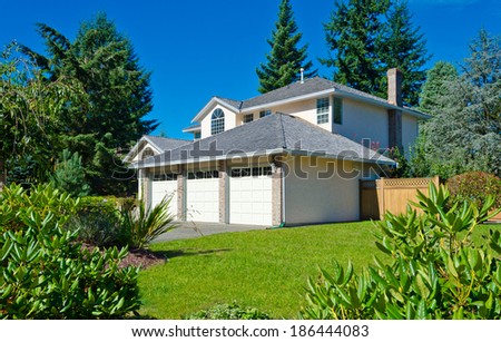Big custom made luxury house with triple doors garage and nicely trimmed and landscaped front yard in the suburbs of Vancouver, Canada.