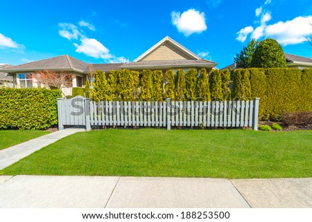County style long wooden fence with nicely trimmed and landscaped front yard.  Landscape trimming design.