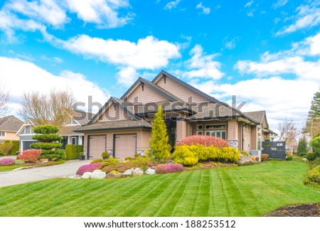 Big custom made luxury house with nicely trimmed and landscaped front yard in the suburbs of Vancouver, Canada.