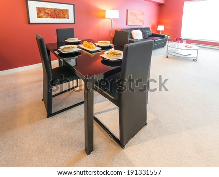 Luxury living suite with red walls: nicely decorated and served dining table. Interior design.