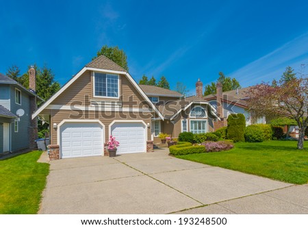 Custom built luxury house with nicely trimmed front yard, lawn and long driveway  to garage in residential neighborhood. Vancouver Canada.