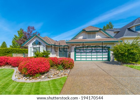 Custom built luxury house with nicely trimmed and landscaped front yard and driveway to double doors garage in residential neigborhood. Vancouver, Canada.