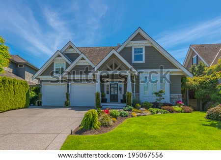 Big custom made luxury house with nicely landscaped front yard and long and wide driveway to garage in the suburb of Vancouver, Canada.