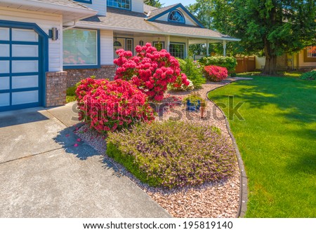 Great neighborhood. Nicely decorated flowerbed, front yard, lawn with colorful bushes as a decorative elements. Landscape design.