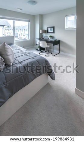 Luxury nicely decorated modern bedroom with some elements of den, home office with the table and the office chair at the back. Interior design of a brand new house.