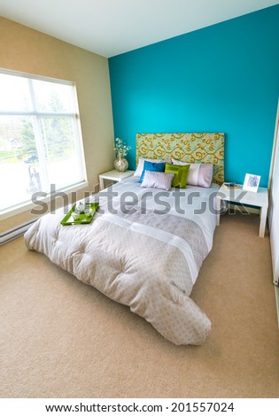 Modern comfortable, nicely decorated master, children bedroom painted in blue, and tray with the tea, coffee set on the bed. Interior design. Vertical.