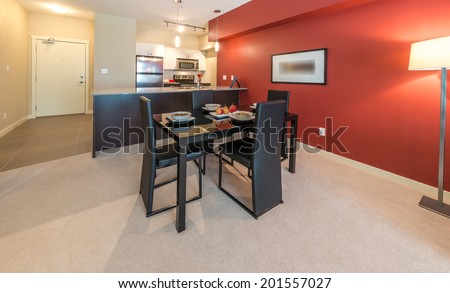 Luxury living suite with red walls: nicely decorated and served with pasta and fruits dining table and the kitchen at the back. Interior design.