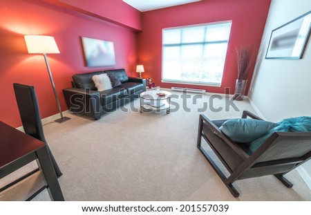 Perspective, outlook at the luxury living suite of the brand new house: nicely decorated  living room with red walls, leather couch and coffee table. Interior design.