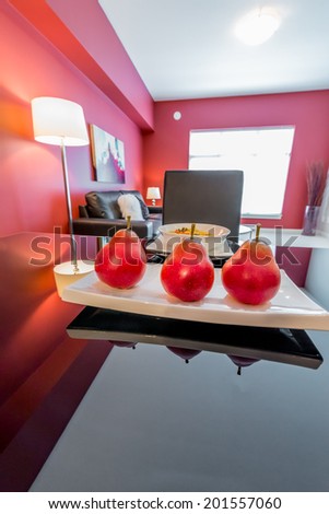 Luxury living suite with red walls: nicely decorated and served dining table with some fruits, pears. Interior design.