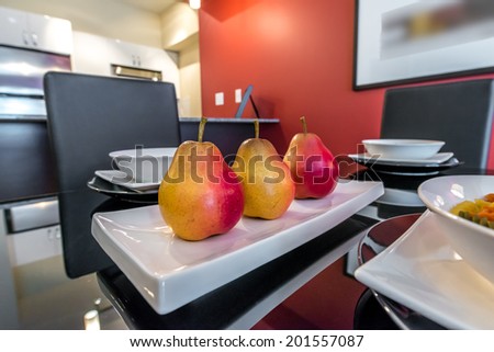 Luxury living suite with red walls: nicely decorated and served dining table with some fruits, pears. Interior design.