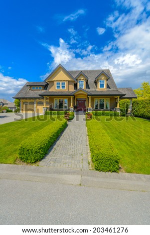 Big custom made luxury house with nicely trimmed and  landscaped front yard and long doorway in the suburb of Vancouver, Canada.