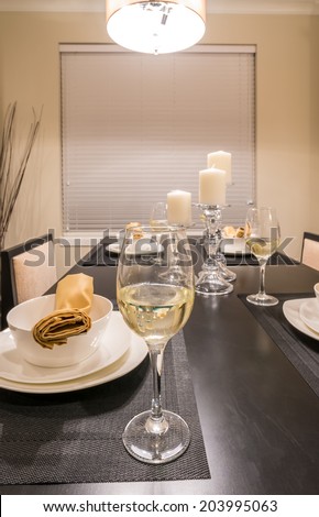 Glass of vine,napkins and candle holders on the nicely decorated and served dining table. Interior design of a brand new house.