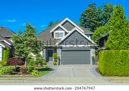 Custom built luxury house with nicely trimmed front yard, lawn and driveway to garage in a residential neighborhood. Vancouver Canada.