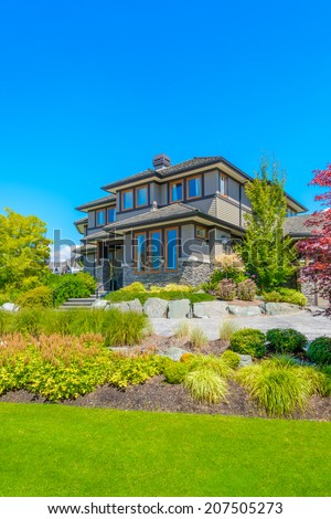 Custom built luxury house with nicely trimmed and designed front yard, lawn in a residential neighborhood. Vancouver Canada. Vertical.