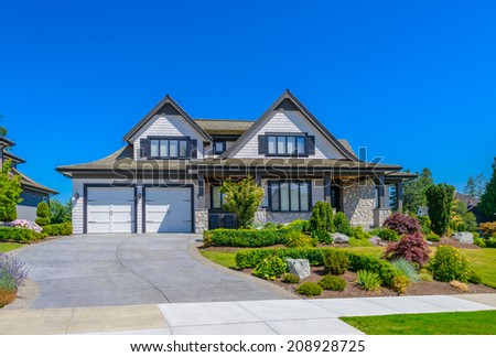 Custom built luxury house with nicely trimmed front yard, lawn and driveway to garage  in a residential neighborhood. Vancouver Canada.
