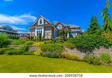 Custom built luxury house with nicely trimmed and landscaped front yard, lawn in a residential neighborhood. Vancouver Canada.