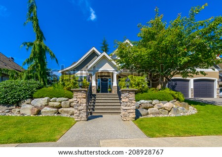 Custom built luxury house with nicely paved and stoned doorway and trimmed front yard, lawn in a residential neighborhood. Vancouver Canada.