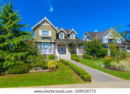 Custom built luxury house with nicely paved doorway and trimmed front yard, lawn in a residential neighborhood. Vancouver Canada.