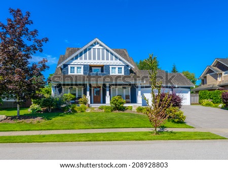 Custom built luxury house with nicely trimmed front yard, lawn and driveway to garage  in a residential neighborhood. Vancouver Canada.