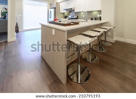 Interior design of a luxury modern kitchen with some sits in a bar style at the island counter.