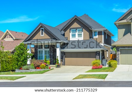Big custom made luxury house with nicely landscaped front yard and driveway to garage in the suburbs of Vancouver, Canada.