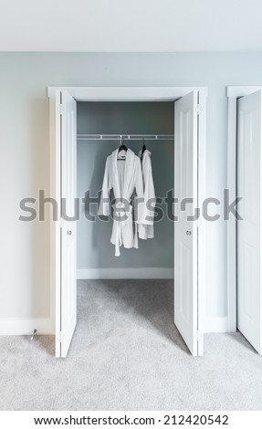 Two bathrobes hanging on a racks in the closet. Interior design. Vertical.