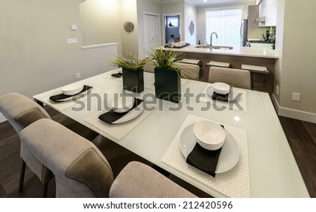 Nicely decorated dining table with cups, plates and napkins and the kitchen at the back. Interior design.
