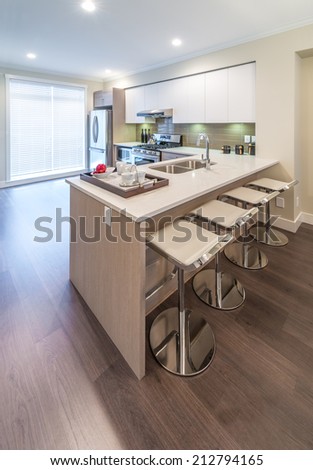 Interior design of a luxury modern kitchen with some sits in a bar style at the island counter. Vertical.