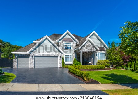 Big custom made luxury house with nicely landscaped front yard and driveway to double doors garage in the suburbs of Vancouver, Canada.