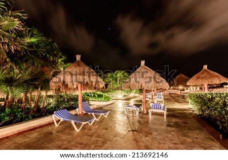 Beach umbrellas at swimming pool at  luxury caribbean resort at night, dawn time. Bahia Principe, Riviera Maya, Mexican Resort.