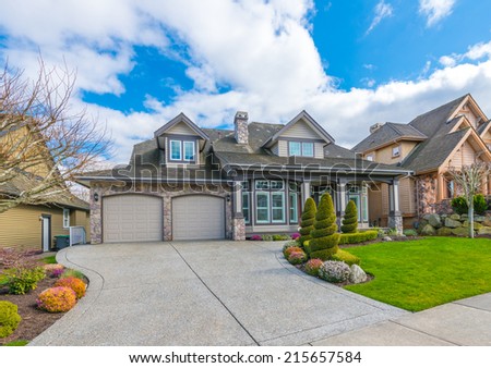 Big custom made luxury house with nicely landscaped front yard, double doors garage and long and wide driveway in the suburbs of Vancouver, Canada.