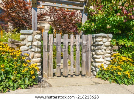 Country looking wooden gates at front, back yard. Flowers and stones as an elements of landscape design.