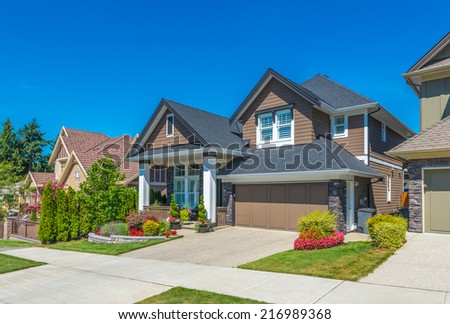 Big custom made luxury house with nicely landscaped front yard and driveway to garage in the suburbs of Vancouver, Canada.