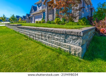 Nicely trimmed lawn grass on the leveled and stoned front yard. Landscape design.