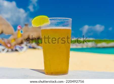 Glass with icy lemonade   ( beer, ice tea ) on the tropical beach of the luxury caribbean resort .