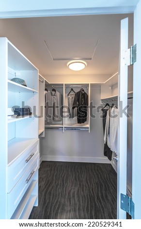 Some garments,   clothing, wear on a poles  and shelves in the closet. Interior design.