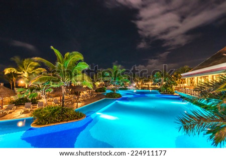 Swimming pool at promenade and restaurant at luxury caribbean resort at night, dawn time. Mexico.