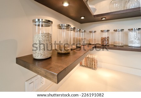 Fragment of the luxury modern kitchen with some shelves with jars, cans in the corner. Interior design.