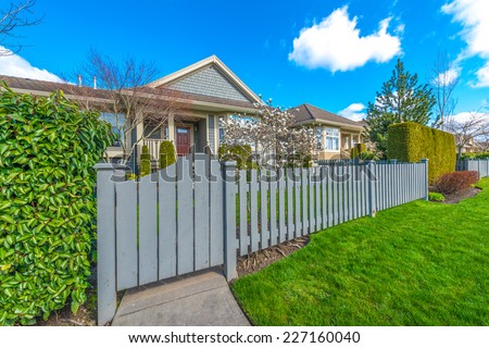 Country style long wooden fence with the gate, wicket and a house behind.