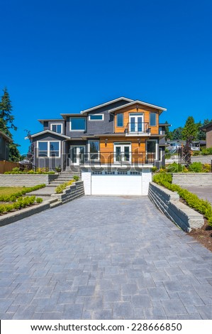 Big custom made luxury modern house with nicely landscaped  front yard and paved driveway to garage in the suburbs of Vancouver, Canada. Vertical.