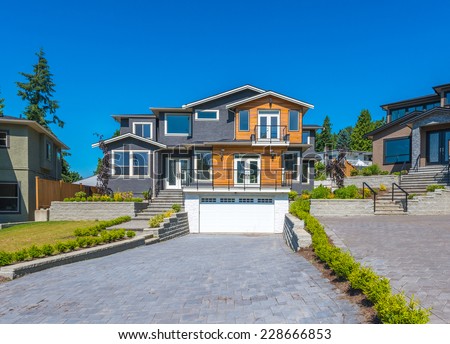 Big custom made luxury modern house with nicely landscaped  front yard and paved driveway to garage in the suburbs of Vancouver, Canada.