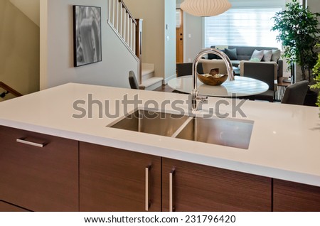 Kitchen counter with the sink and dining table and living room at the back. Interior design of new house.