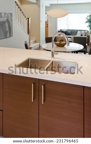 Kitchen counter with the sink and dining table and living room at the back. Interior design of new house. Vertical.