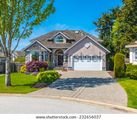 Custom built luxury house with nicely trimmed front yard, lawn and driveway to garage in a residential neighborhood. Vancouver Canada.