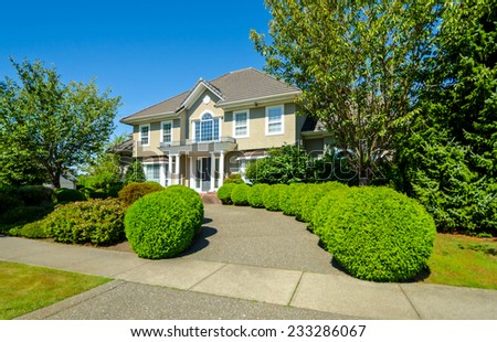 Big custom made luxury house with nicely landscaped and trimmed front yard and paved doorway in the suburbs of Vancouver, Canada.