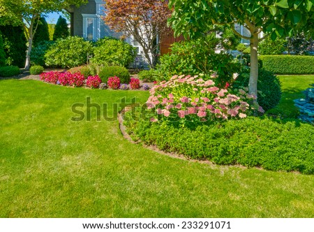Flowers and nicely trimmed bushes in front of the house, front yard. Landscape design.