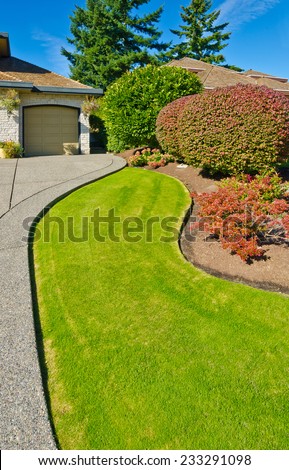 Flowers and stones and nicely trimmed bushes in front of the house, front yard. Landscape design.